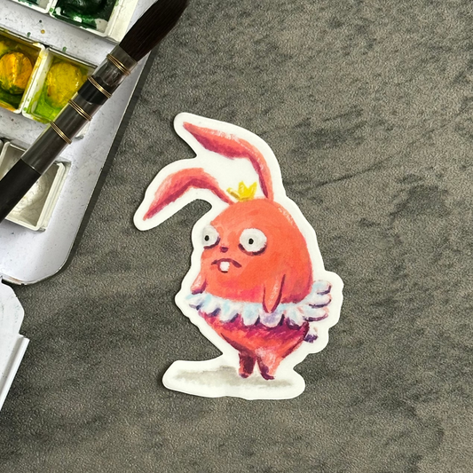 Pink bunny with a round body in a tutu and crown. it appears to have stage fright. vinyl sticker