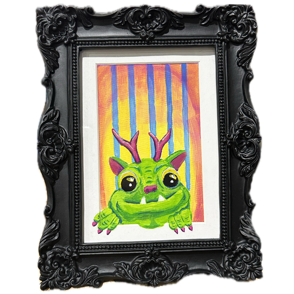 Baroque black frame of a painting of a green monster creature who appears to be climbing out of the mat